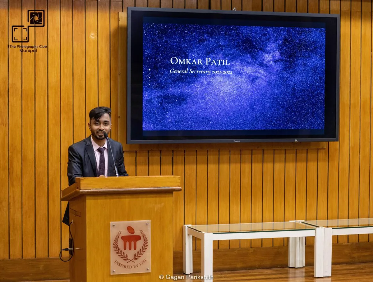 Omkar speaking at a podium at MIT Manipal